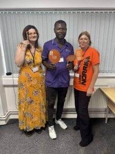 Two women wearing orange and a male carer posing.