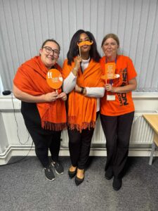 Three members of staff from CRT wearing orange and smiling at the camera.