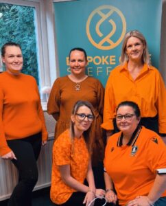 Group of five, all wearing orange with a Bespoke Sheffield banner visible in the background.